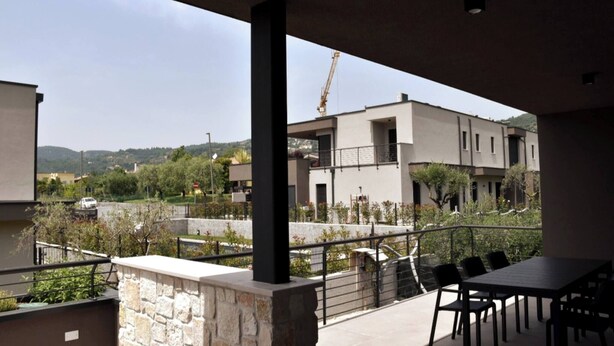 Un balcone con un muro in pietra, un tavolo e delle sedie.