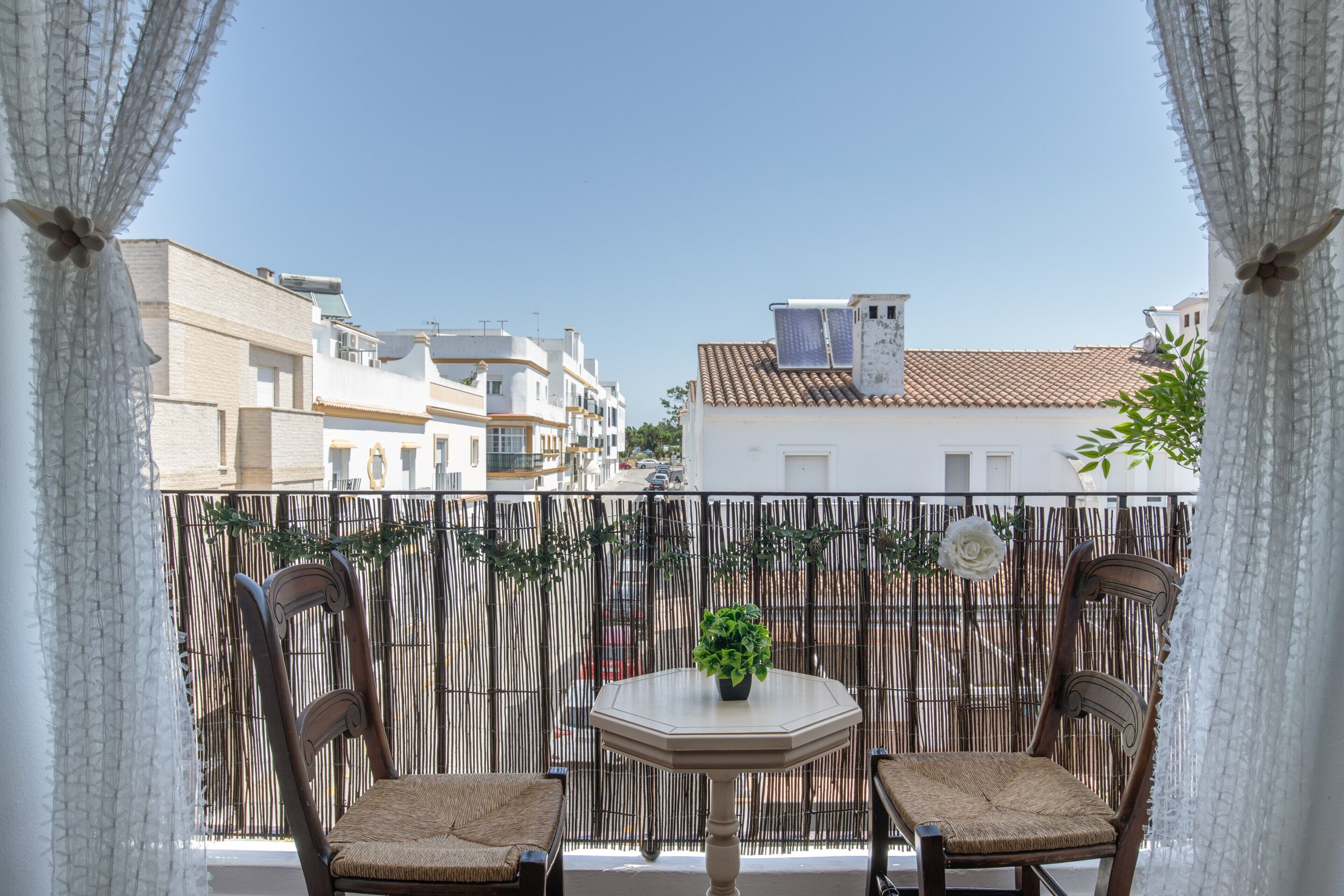 Ein Balkon mit zwei Korbstühlen, einem kleinen runden Tisch und einem Blumentopf.