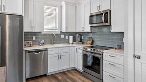 A modern kitchen with white cabinets, stainless steel appliances, a microwave, and a dishwasher. - The CODtage is amazing! 60 steps from beach, 2.5 blks to boardwalk! (Carolina Beach)