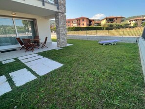 A residential area with a paved patio, outdoor furniture, and a grassy lawn. - Villetta Sabri - Vacation Home in Garda (Garda)