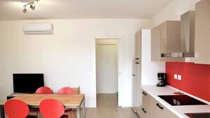 A modern kitchen with white cabinets, a red accent wall, and a coffee maker on the counter. - Villetta Pima - Holiday Home in Garda (Garda)