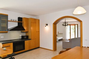 Eine moderne Küche mit Holzschränken, einer schwarzen Mikrowelle und einem Essbereich mit Holztisch und Stühlen.