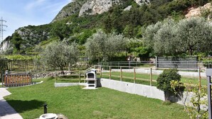 A park with a grassy area, a small white structure, and a stone wall. - Villa Tessari in Rivoli Veronese (Rivoli Veronese)