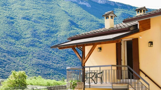 A building with a balcony, a wooden staircase, and a view of a mountainous landscape. - Villa Tessari in Rivoli Veronese (Rivoli Veronese)