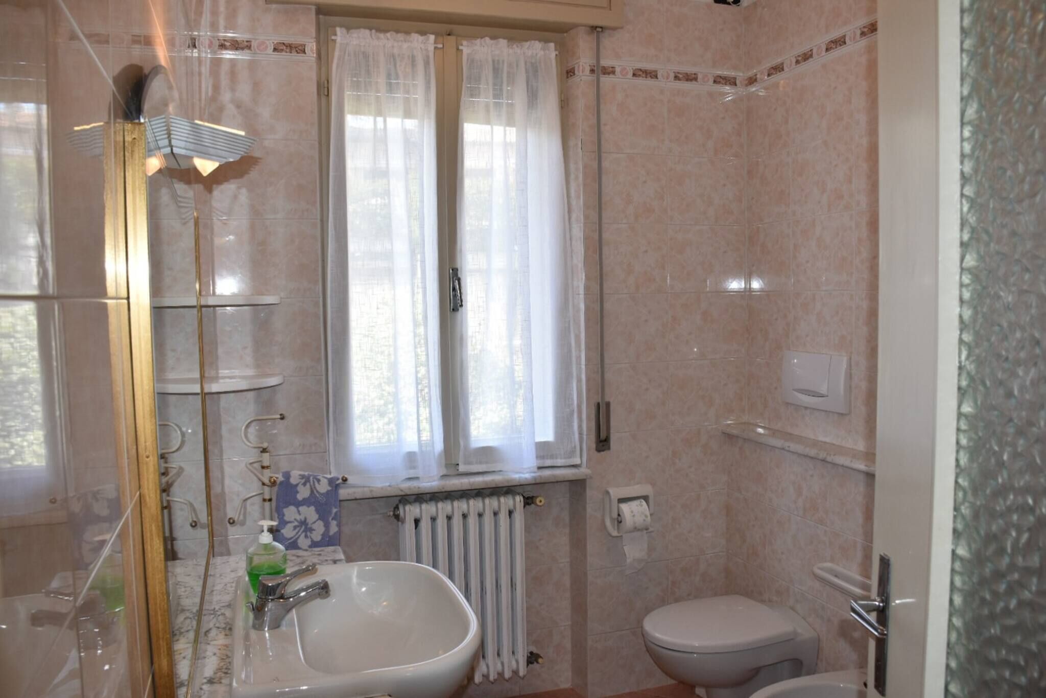 A bathroom with a sink, toilet, and a window with curtains.