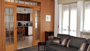 Una sala de estar con sofá, una mesa de centro y una zona de comedor con sillas y una mesa.