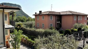 Un edificio de dos plantas con fachada roja, un balcón y vistas a una montaña.