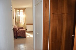A hallway with a wooden door, a patterned chair, and a white wardrobe. - Casa Marina - Holiday Rental (Garda)