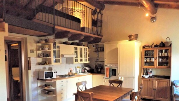 Een kleine keuken met witte kastjes, een houten eettafel en een kleine oven.