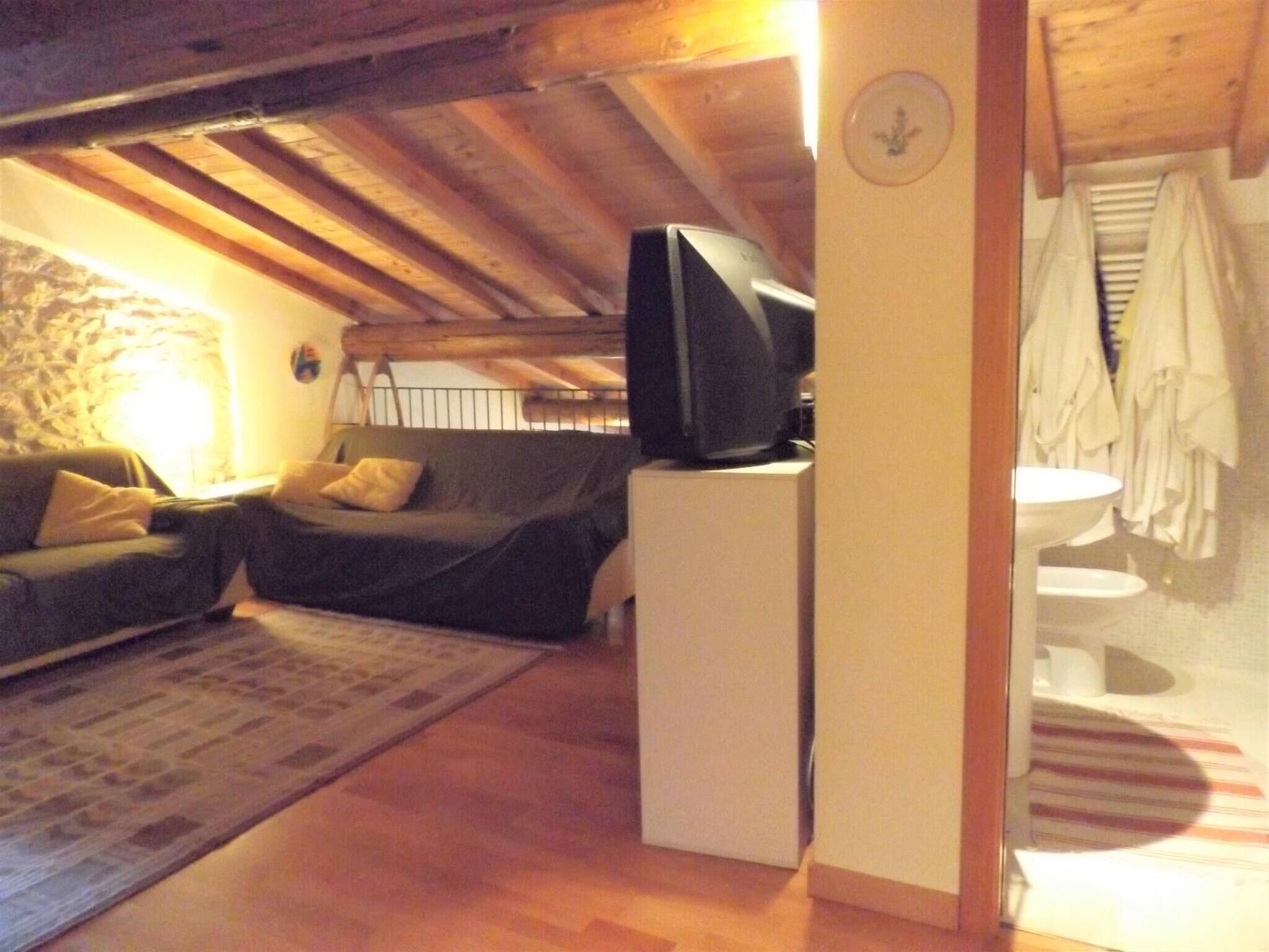 A cozy living room with a sofa, a television, and a small white cabinet.