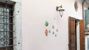 Een roze muur met een decoratieve lamp en meerdere kleurrijke wanddecoraties.