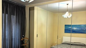 Un dormitorio con cama, espejo, un cuadro y una araña.