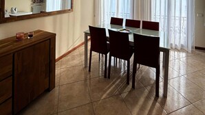 Un comedor con una mesa, sillas, un aparador de madera y un ventanal con cortinas.