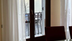 Una habitación con puerta de vidrio que da a un espacio exterior con mesas y sillas.