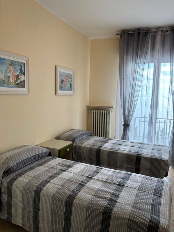 Une chambre avec deux lits, un radiateur et deux tableaux encadrés au mur.