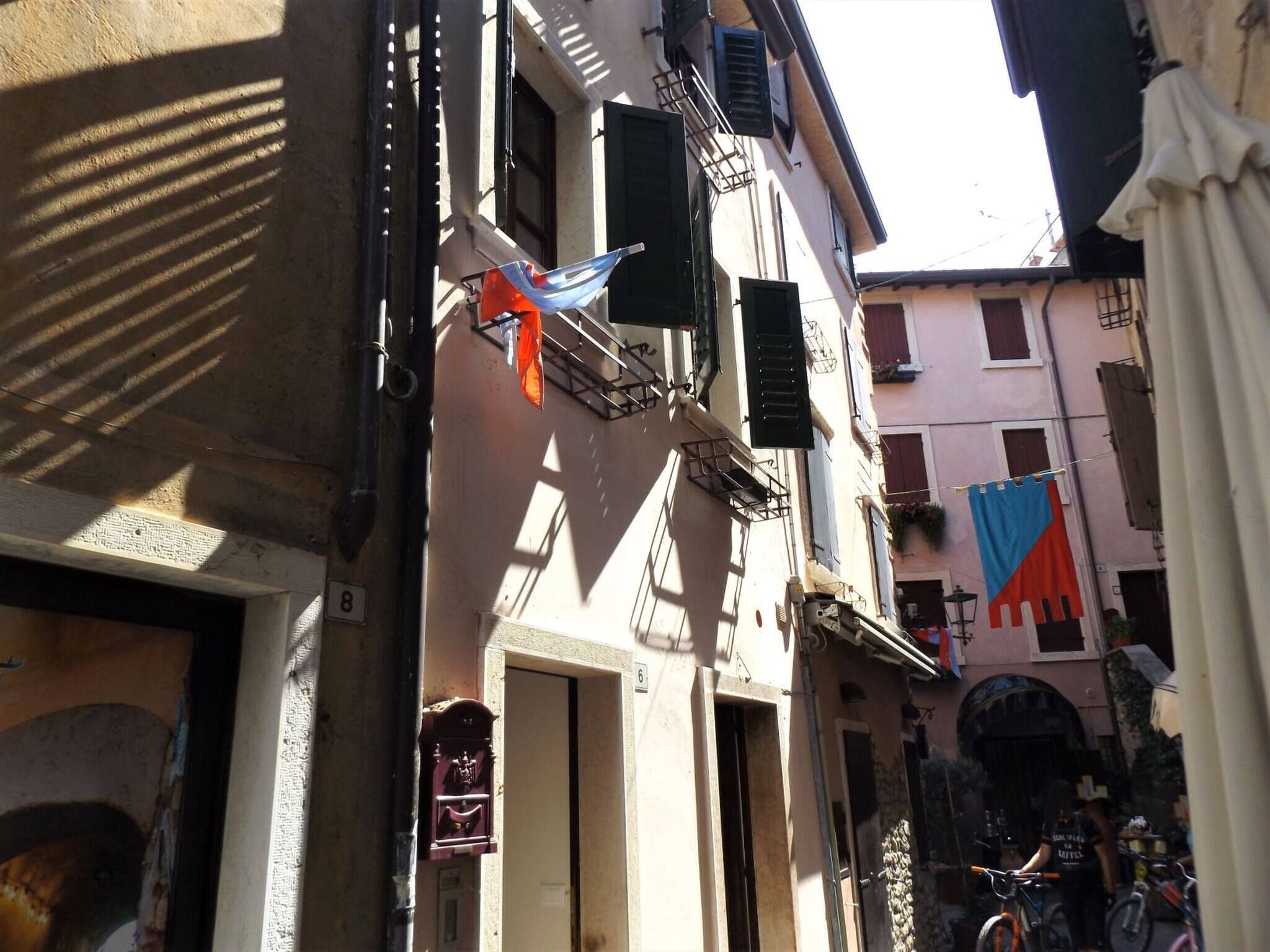 Une rue étroite, bordée de bâtiments des deux côtés, avec une boîte aux lettres bien visible et un vélo garé sur le côté droit.