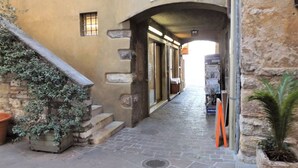 A narrow alleyway with a stone wall on one side, a wooden staircase on the other, and a sign above an archway that reads "Barbiere". - Catullo House in Garda (Garda)