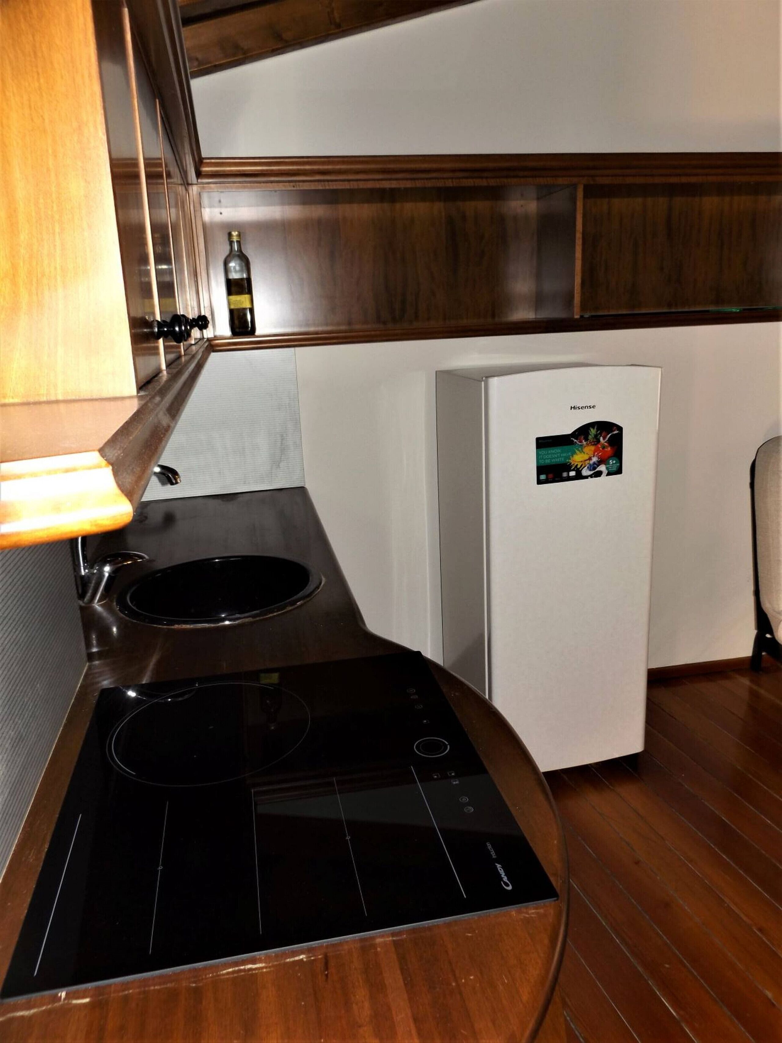 Uma cozinha compacta com fogão embutido, um frigorífico pequeno e um armário de madeira.