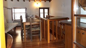 A compact room with a wooden ceiling, a bed, a table, and chairs. There are windows providing natural light. - Catullo House in Garda (Garda)