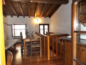 A compact room with a wooden ceiling, a bed, a table, and chairs. There are windows providing natural light. - Catullo House in Garda (Garda)