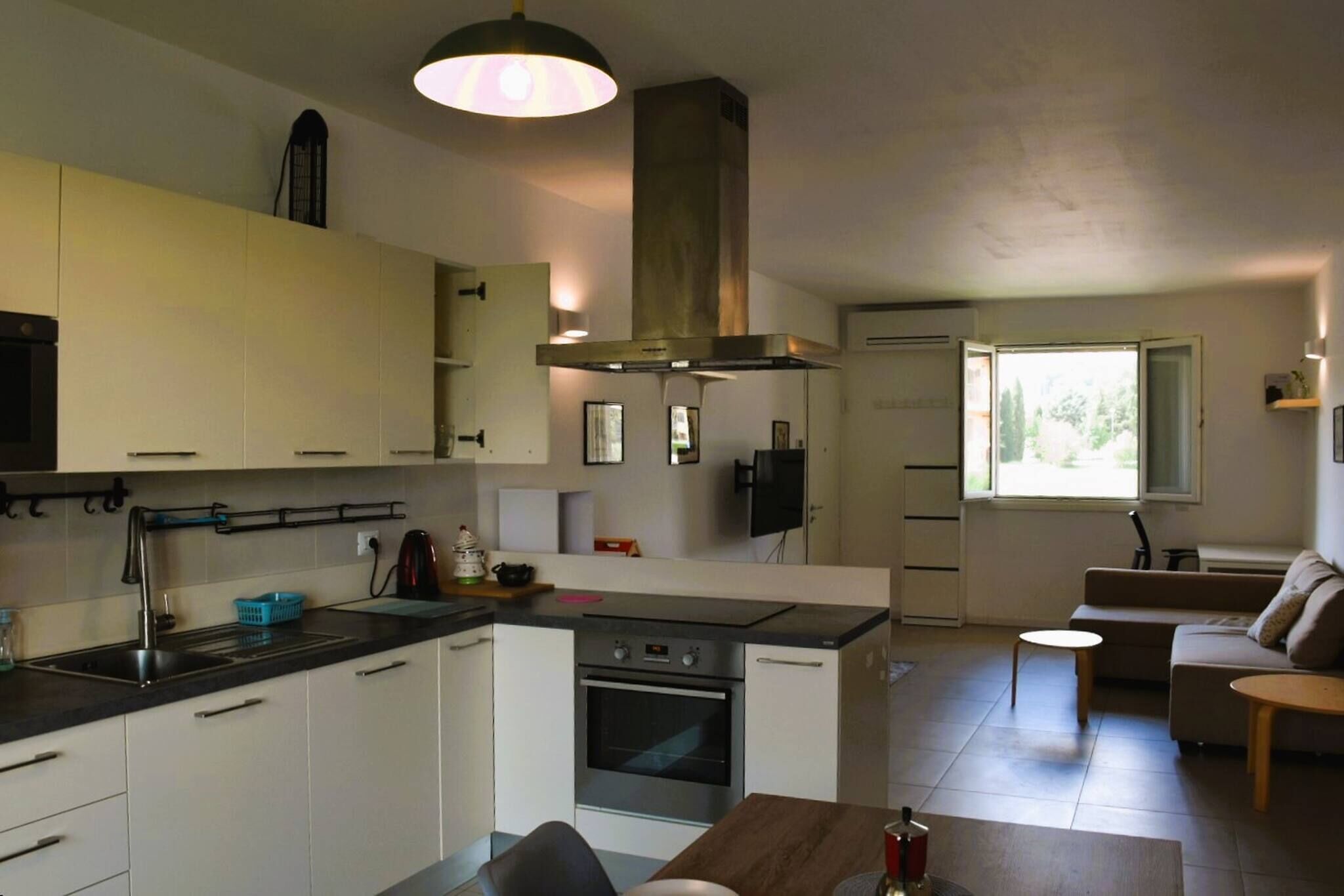A compact kitchen with a central island, a built-in oven, and a large window providing natural light.