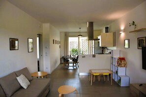 Una sala moderna con sofá, mesa de comedor y zona de cocina.
