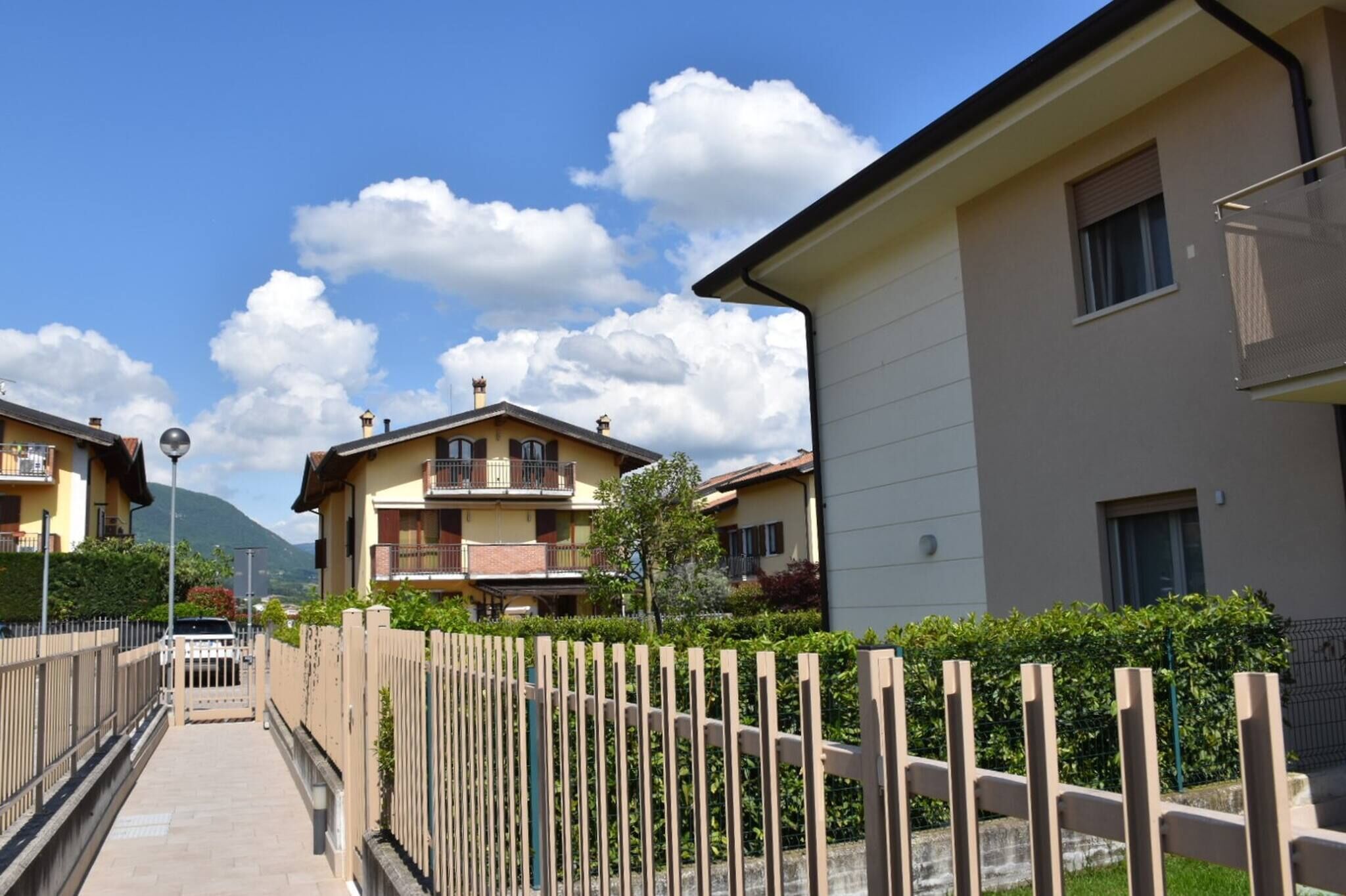 Zona residencial con edificios de varios pisos, entrada vigilada y cielo despejado.