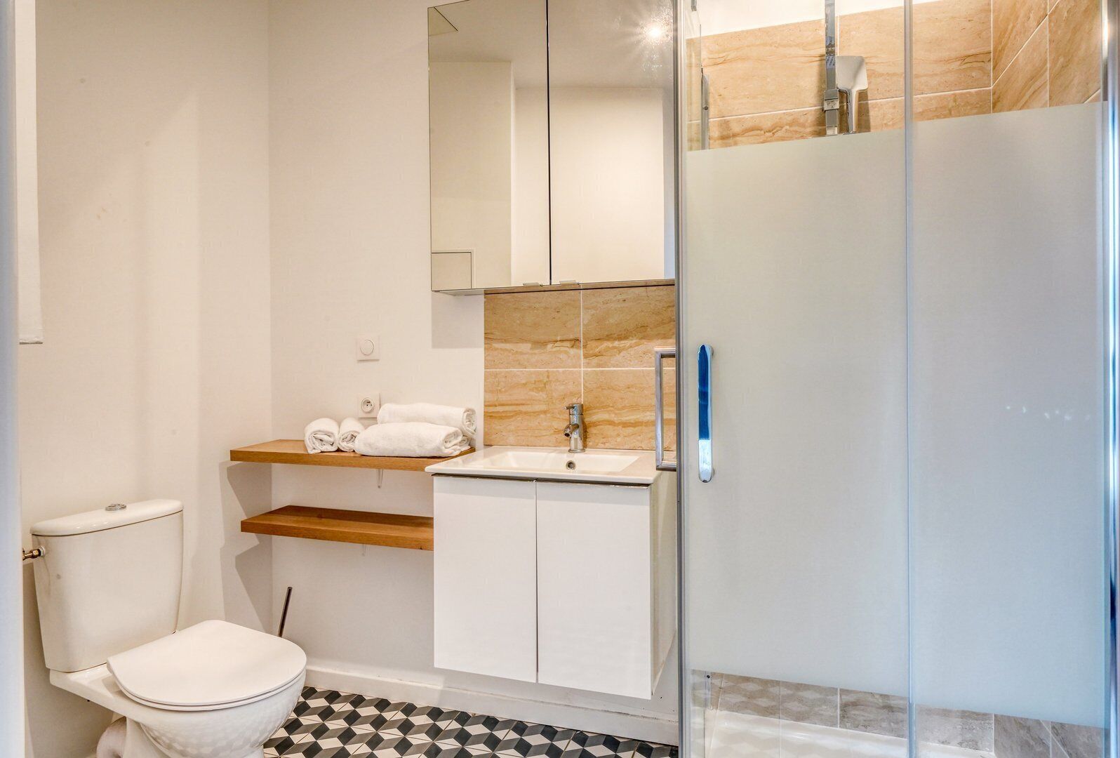 Un baño moderno con inodoro, lavamanos y cabina de ducha de vidrio.