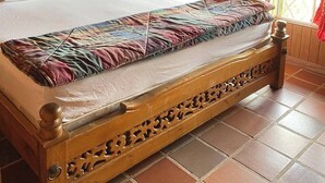 Um quarto com painéis de madeira, uma cama grande, cortinas vermelhas e piso de azulejos.