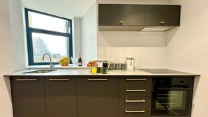 Una cocina moderna con horno empotrado, una ventana y una encimera con diversos objetos.