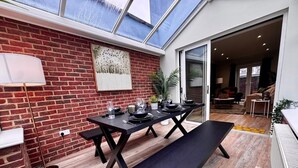 Een eetgedeelte met een bakstenen muur, een tafel voor vier personen en een bank.