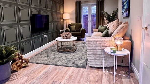 Een moderne woonkamer met een bank, een salontafel en een aan de muur bevestigde televisie.