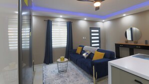 A modern bedroom with a ceiling fan, a bed, a bedside table, and a dresser.