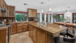A modern kitchen with wooden cabinets, a granite island, and pendant lighting. - Luxe Chapel Retreat |Chapel Views|Swim Spa | Sauna (Sedona)