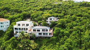 Ein mehrstöckiges Resort mit einem zentralen Gebäude, umgeben von üppiger Vegetation, mit Balkonen und einem Schwimmbad.