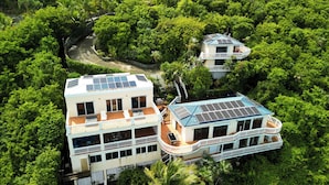 Ein zweistöckiges Haus mit Balkon, umgeben von üppiger Vegetation.