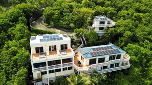 A two-story house with a balcony, surrounded by lush greenery. - The Breeze Villa, newest ocean front boutique oasis (St Thomas)