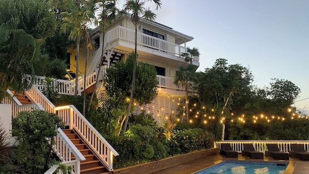 Ein Schwimmbecken mit Holzterrasse, einer Treppe und einem Balkon.
