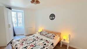 Ett sovrum med en säng, sänglampor, ett element, ett fönster med utsikt och en väggdekoration.