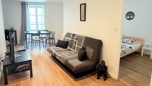 Ett modernt vardagsrum med en soffa, en tv, en matplats och en säng.