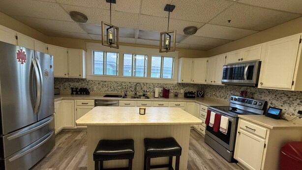 A kitchen with a central island, stainless steel appliances, and a microwave. - Historic District Home with Proud N.M.M.I. Family Legacy (Roswell)