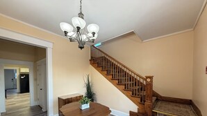 A spacious living area with a wooden staircase, a dining table, and a chandelier. - Historic District Home with Proud N.M.M.I. Family Legacy (Roswell)