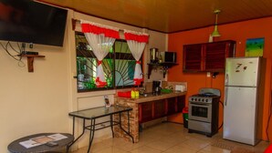 A compact kitchen with a gas stove, refrigerator, and a small dining table. - Hummingbird Villa (La Fortuna)