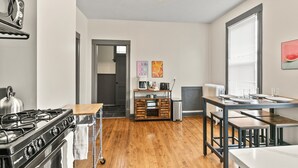 Uma cozinha moderna com fogão a gás, piso de madeira, espaço para café e área de refeições com mesa e bancos.