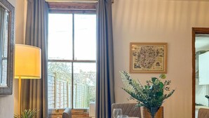 A dining area with a wooden table set for four, a potted plant, and a framed map on the wall. - New | Cosy & Stylish City Centre Home | Sleeps 6 (Canterbury)