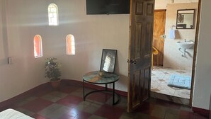 Une pièce avec un sol à carreaux, une porte en bois, une petite table avec une chaise et une plante en pot.