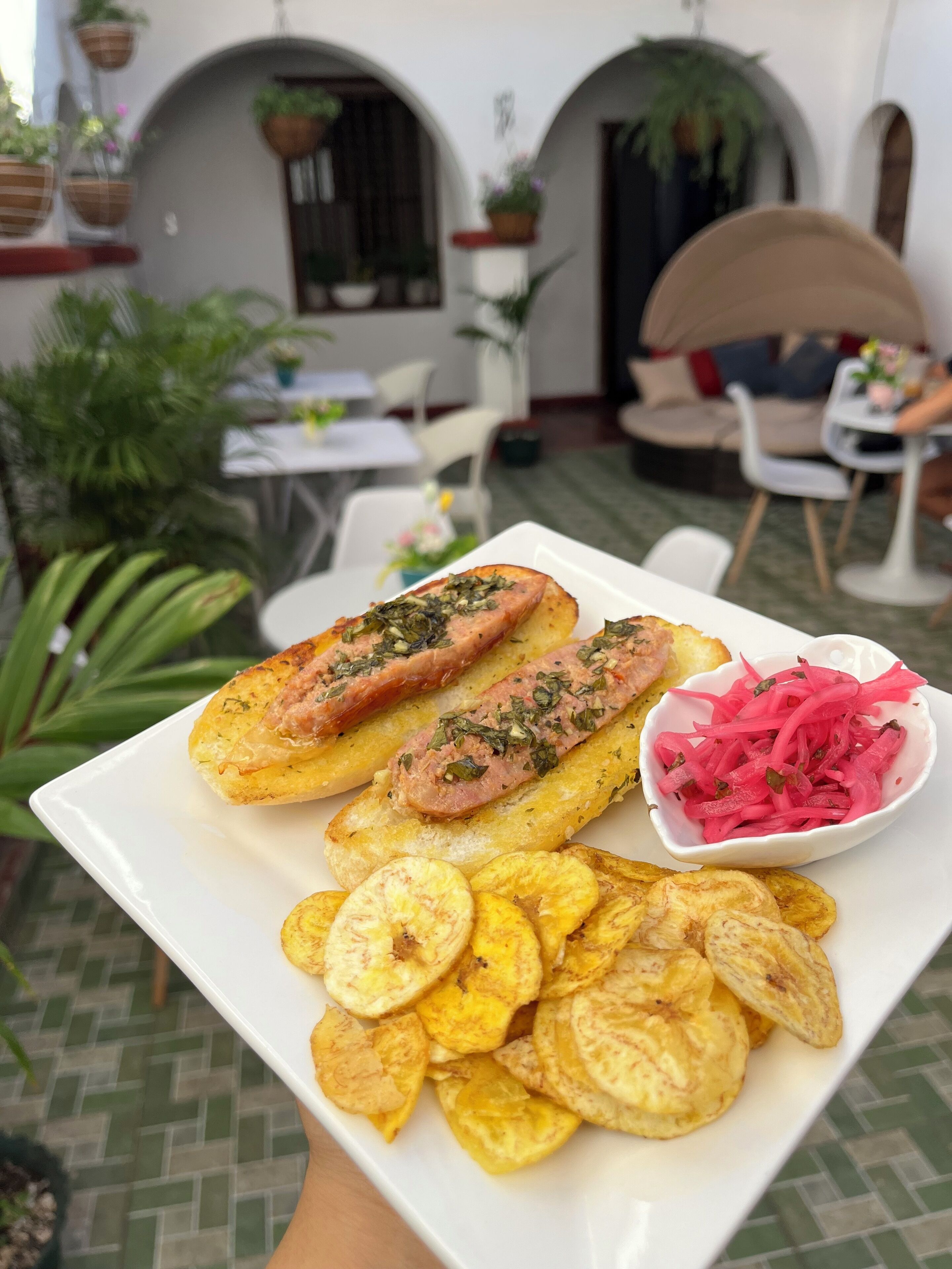 A plate with food items, a table, chairs, and potted plants in a dining area.