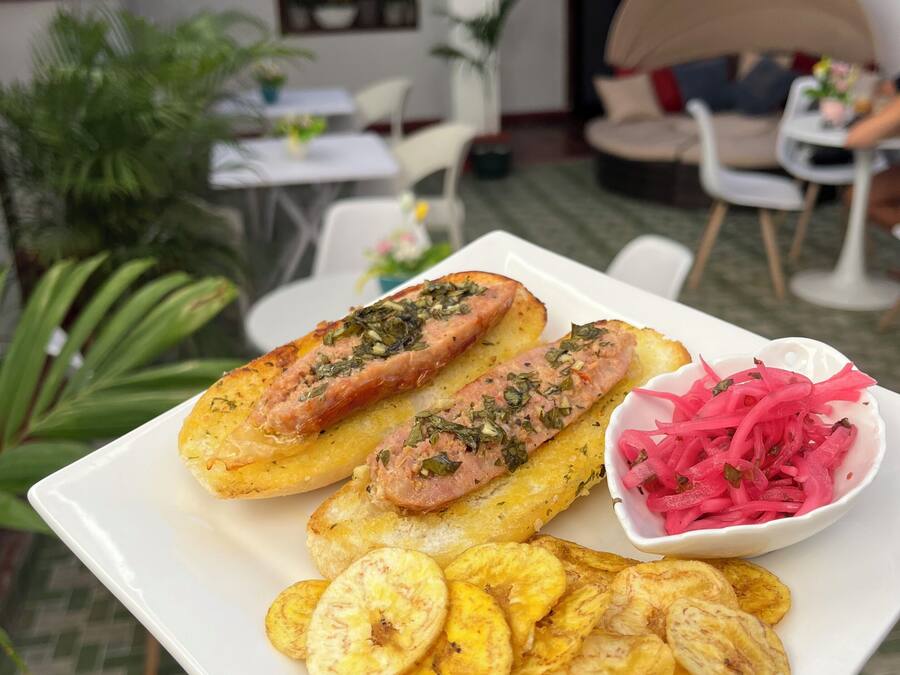 A plate with food items, a table, chairs, and potted plants in a dining area.
