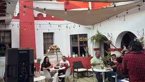Une terrasse extérieure avec des tables, des chaises et un ordinateur portable posé sur un support.
