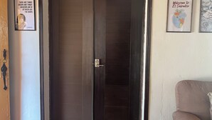 Une porte en bois sombre dotée d’un clavier pour l’ouverture, une citation encadrée accrochée au mur et une pancarte d’accueil encadrée.